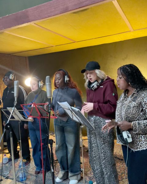 Gospel singers recording around studio microphones